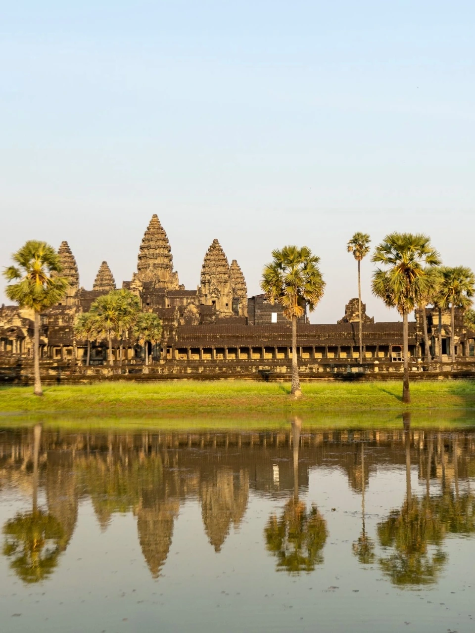 Angkor Wat v teplém ranním světle se zrcadlí na hladině