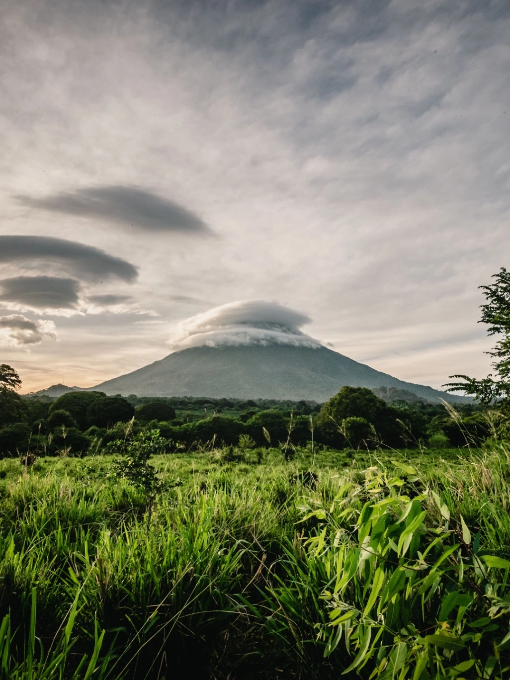 Sopka Arenal při západu slunce nad svěží tropickou krajinou Kostariky