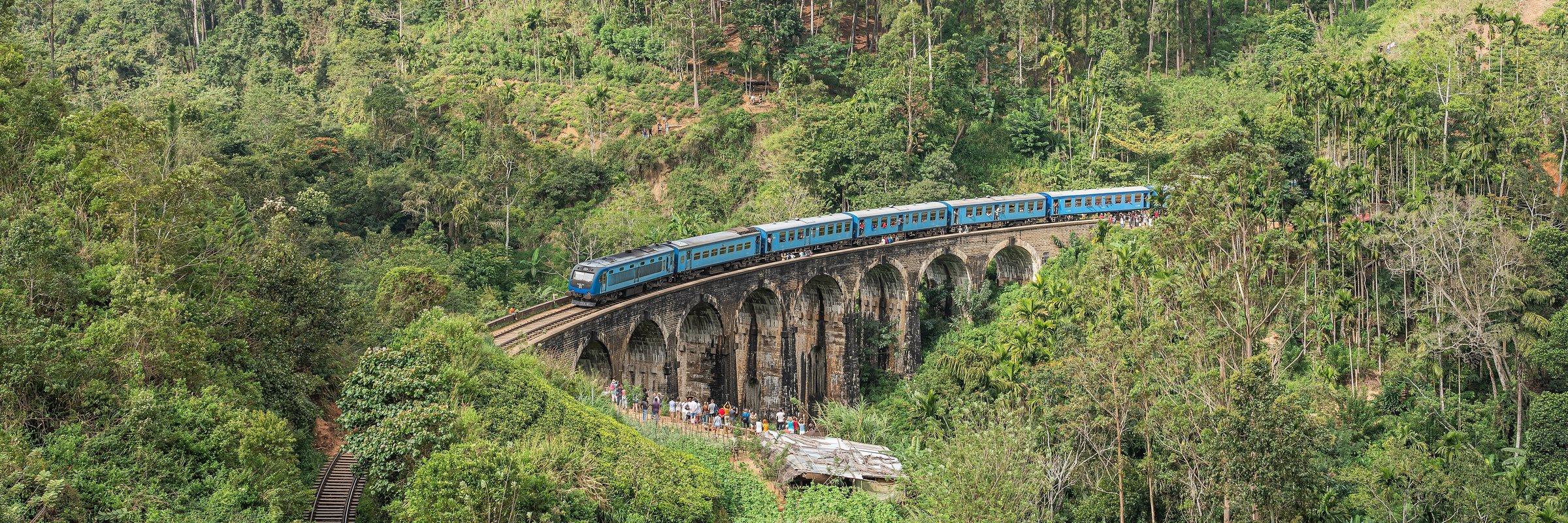 Modrý vlak přejíždí viadukt v čajových horách u Elly